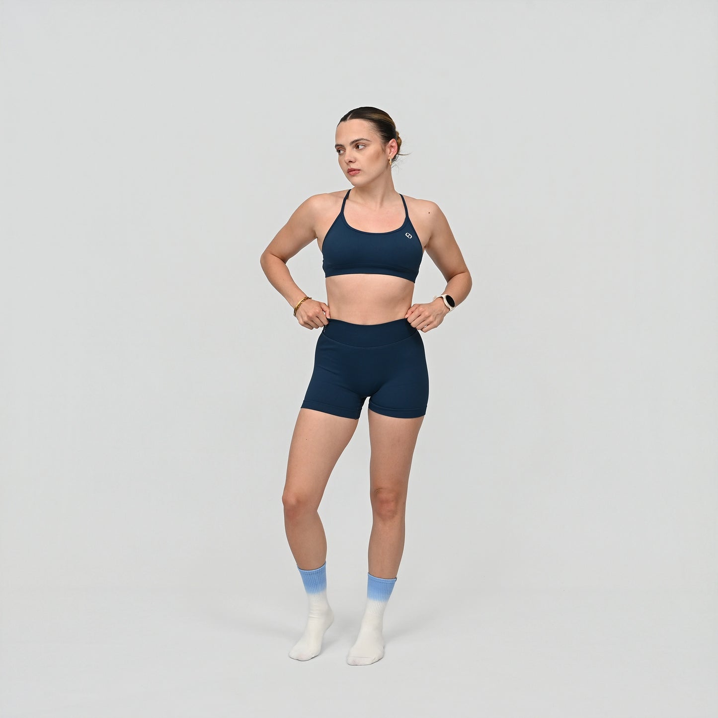 Woman wearing a teal Hybryd sports bra and matching booty shorts