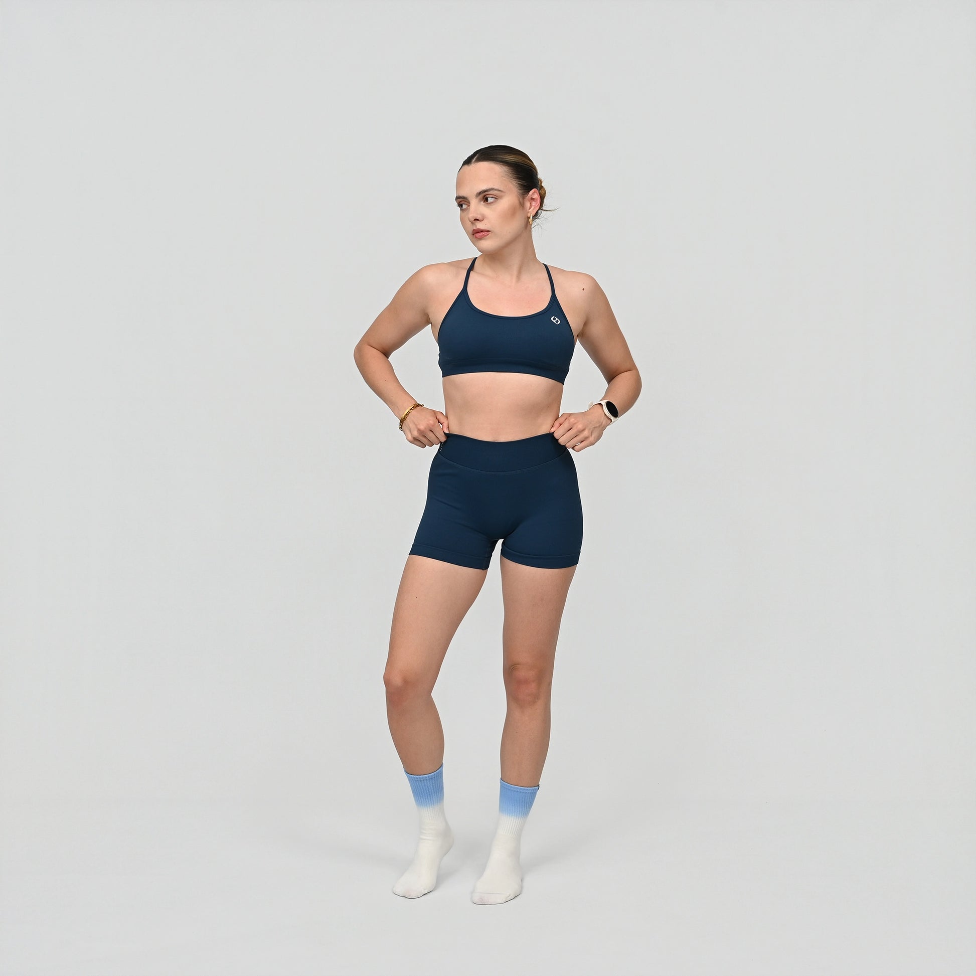Woman wearing a teal Hybryd sports bra and matching booty shorts
