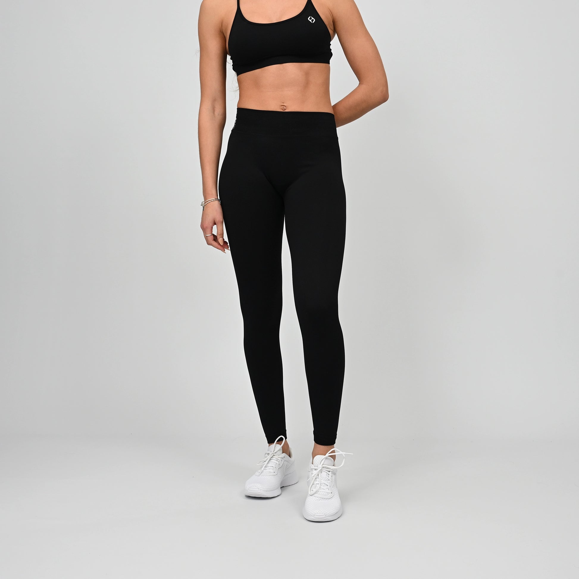 Girl wearing black Hybryd equinox leggings that have a v-dip rear waist and a scrunch bum. From activewear brand Hybryd