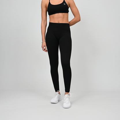 Girl wearing black Hybryd equinox leggings that have a v-dip rear waist and a scrunch bum. From activewear brand Hybryd