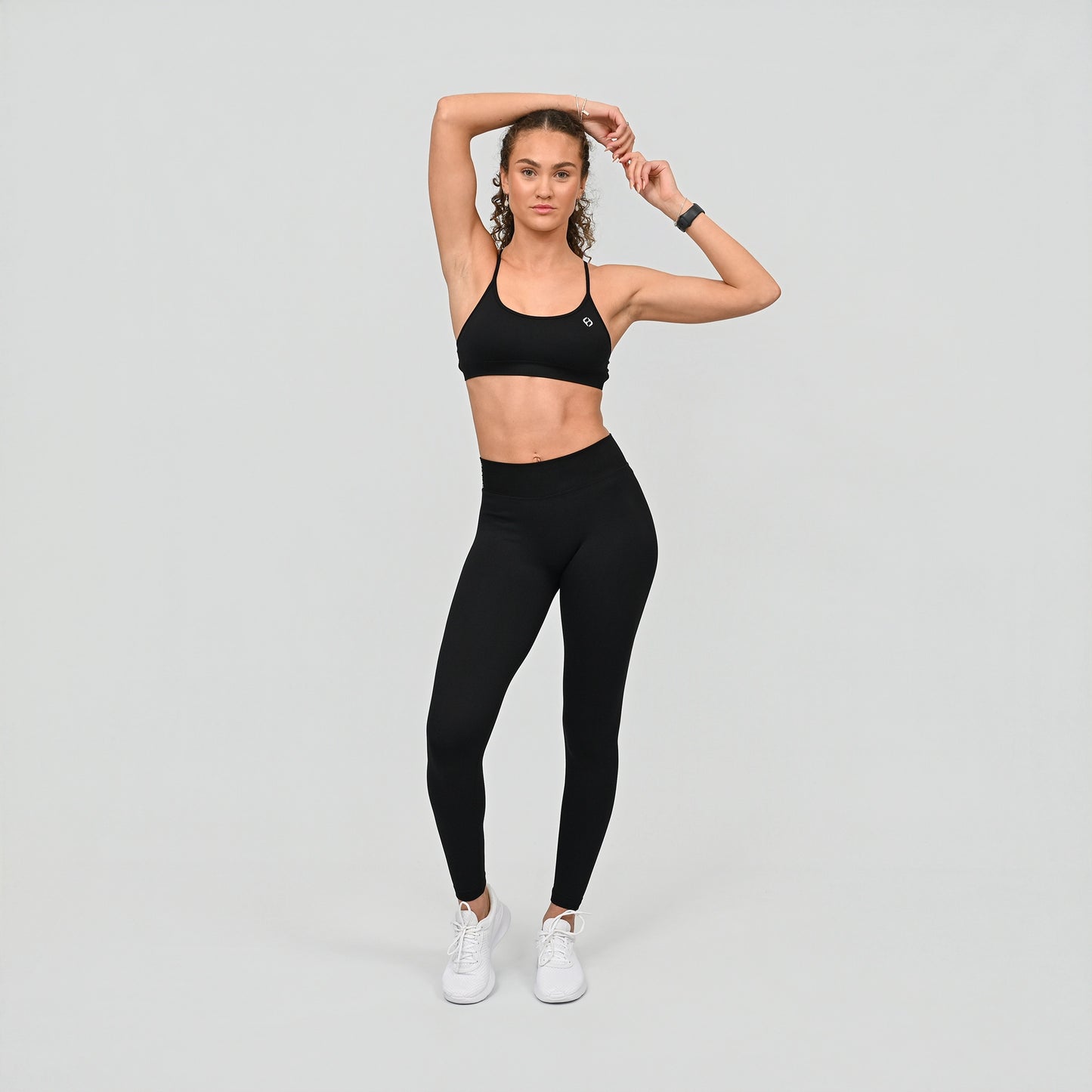 Girl wearing black Hybryd set. Equinox leggings that have a v-dip rear waist and a scrunch bum. Teamed with matching blac bra. From activewear brand Hybryd