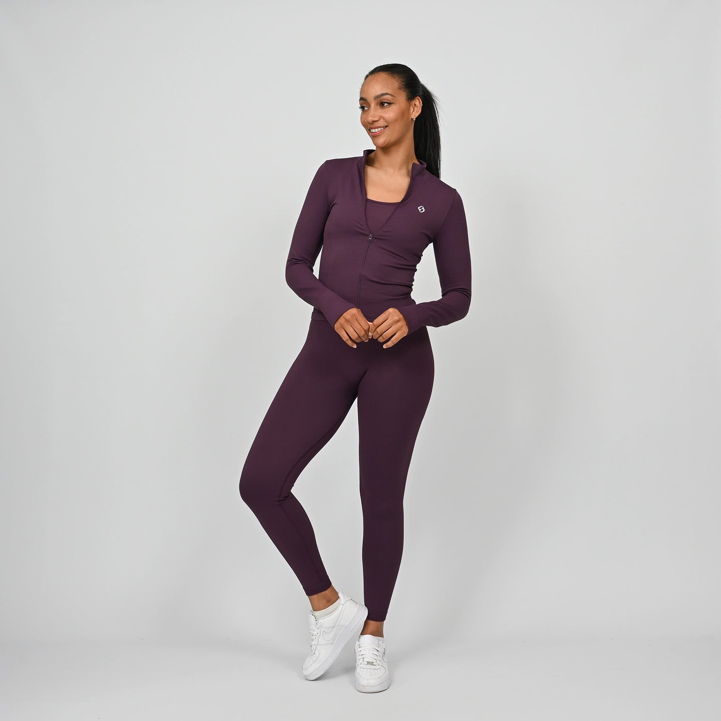 Woman wearing a purple athletic outfit from Hybryd on a grey background