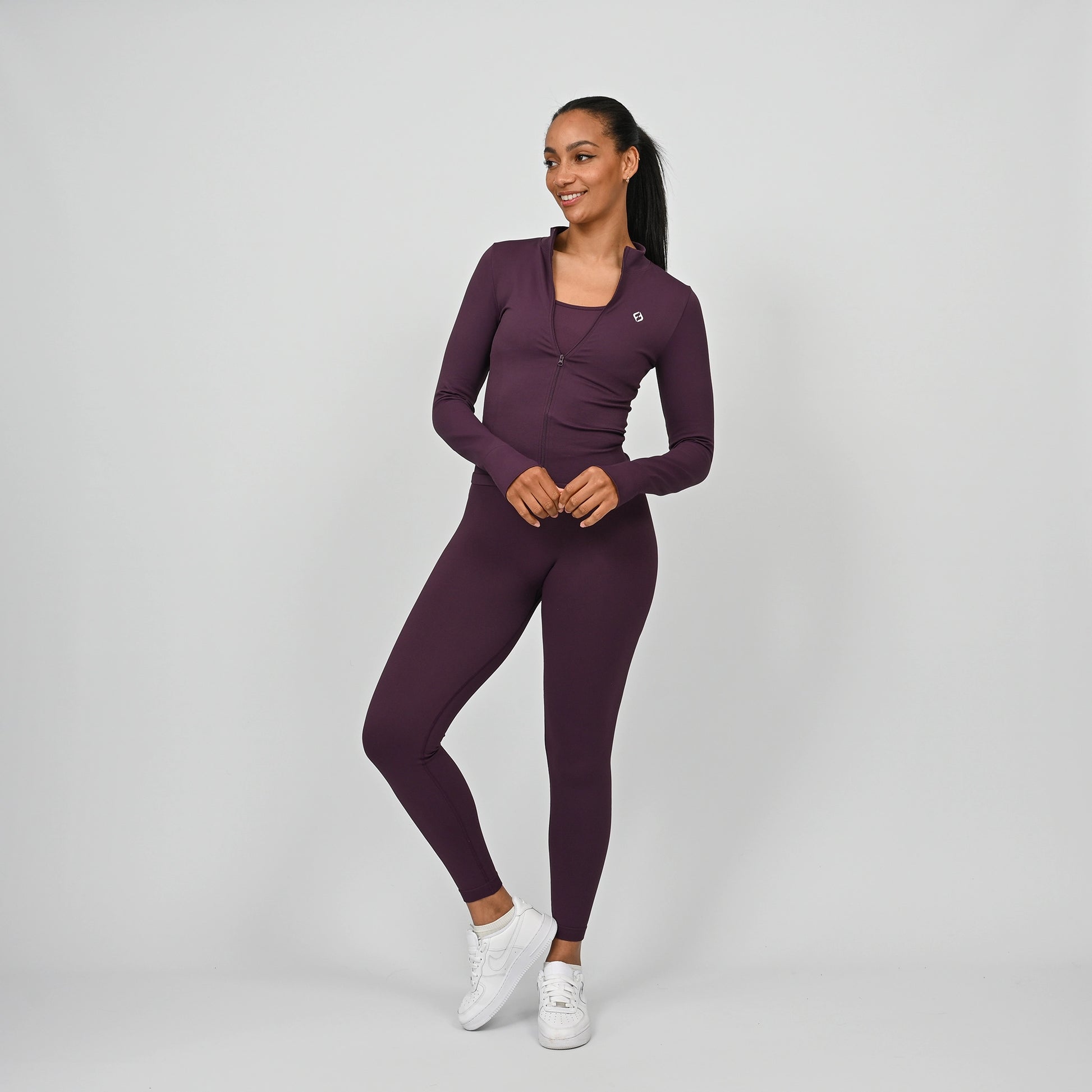 Woman wearing a purple athletic outfit from Hybryd on a grey background