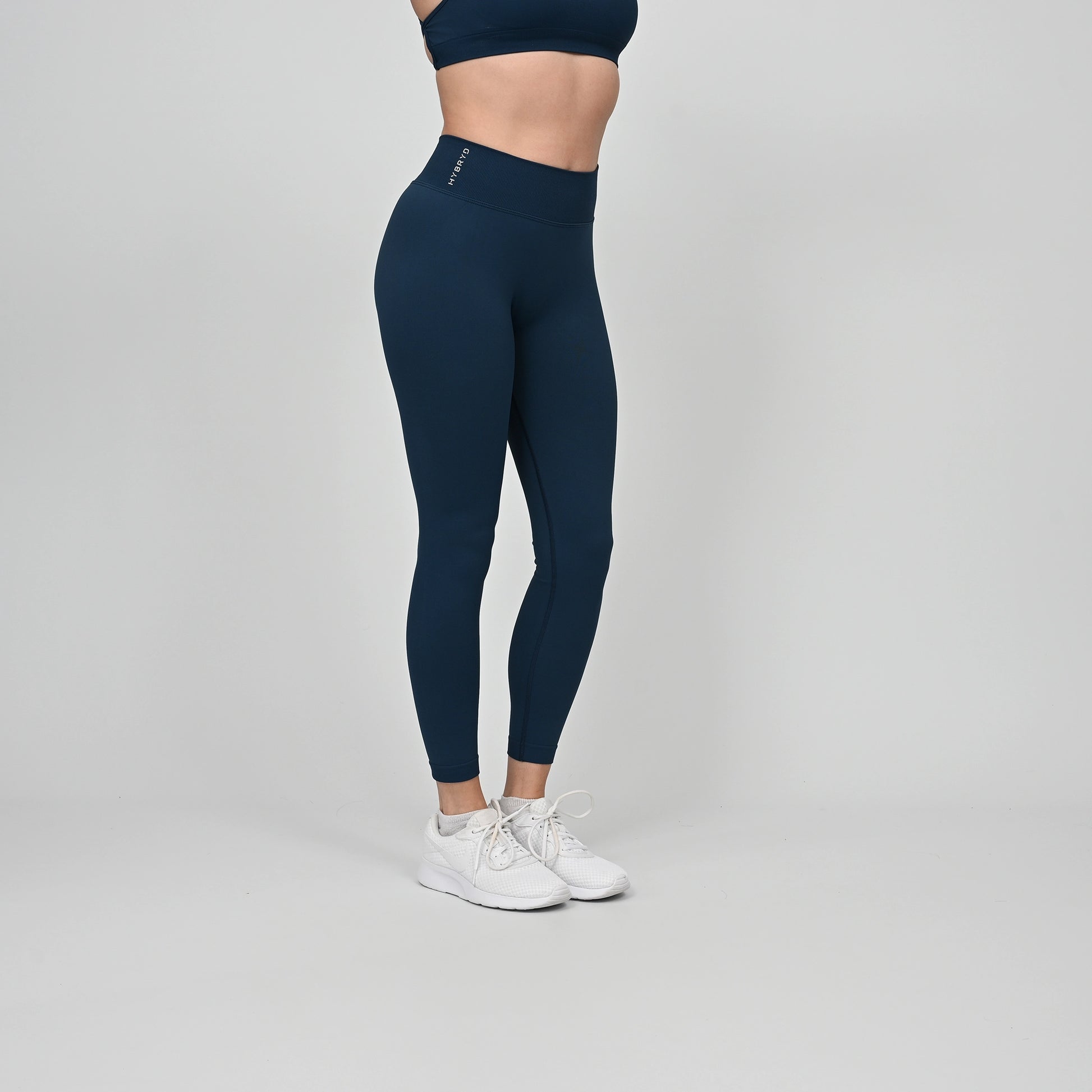 Girl wearing teal Hybryd equinox leggings in teal. that have a v-dip rear waist and a scrunch bum. From gymwear brand Hybryd