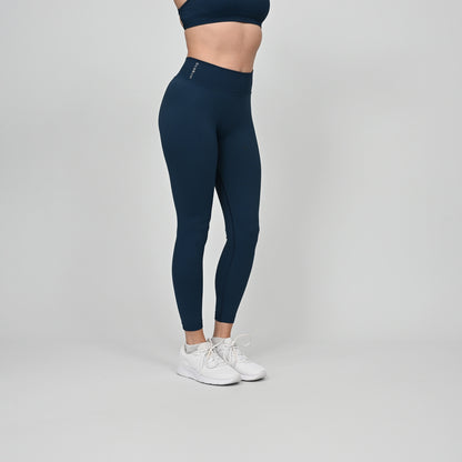 Girl wearing teal Hybryd equinox leggings in teal. that have a v-dip rear waist and a scrunch bum. From gymwear brand Hybryd
