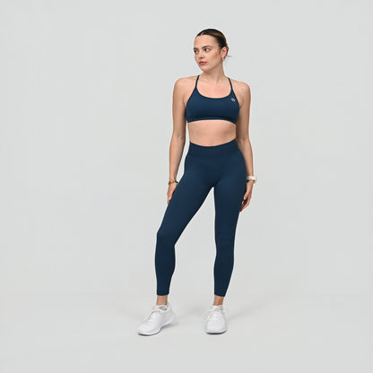 Girl wearing teal Hybryd equinox matching set. Leggings  that have a v-dip rear waist and a scrunch bum. Minimal sports bra with removable pads. From activewear brand Hybryd