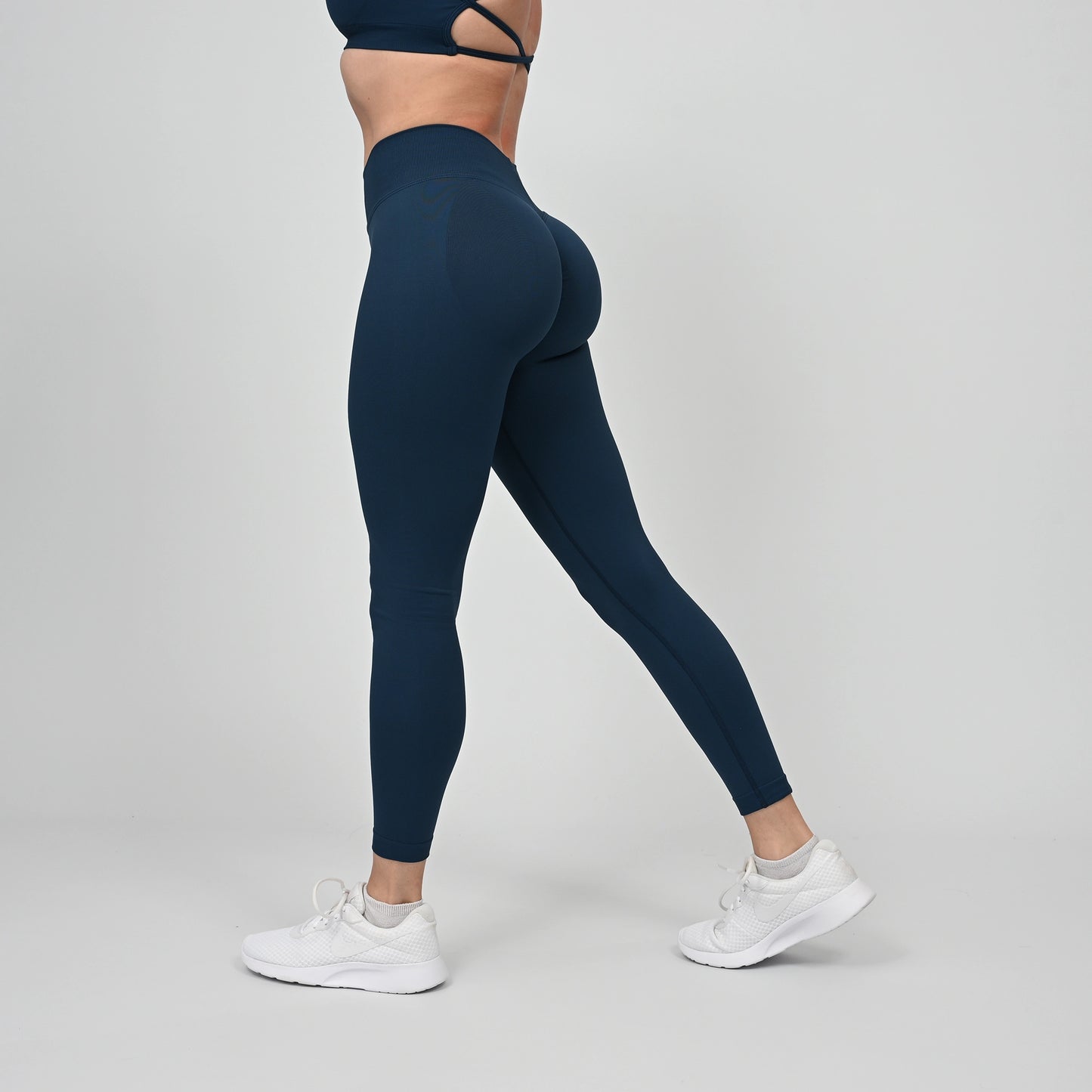 Girl wearing teal Hybryd equinox leggings that have a v-dip rear waist and a scrunch bum. From activewear brand Hybryd