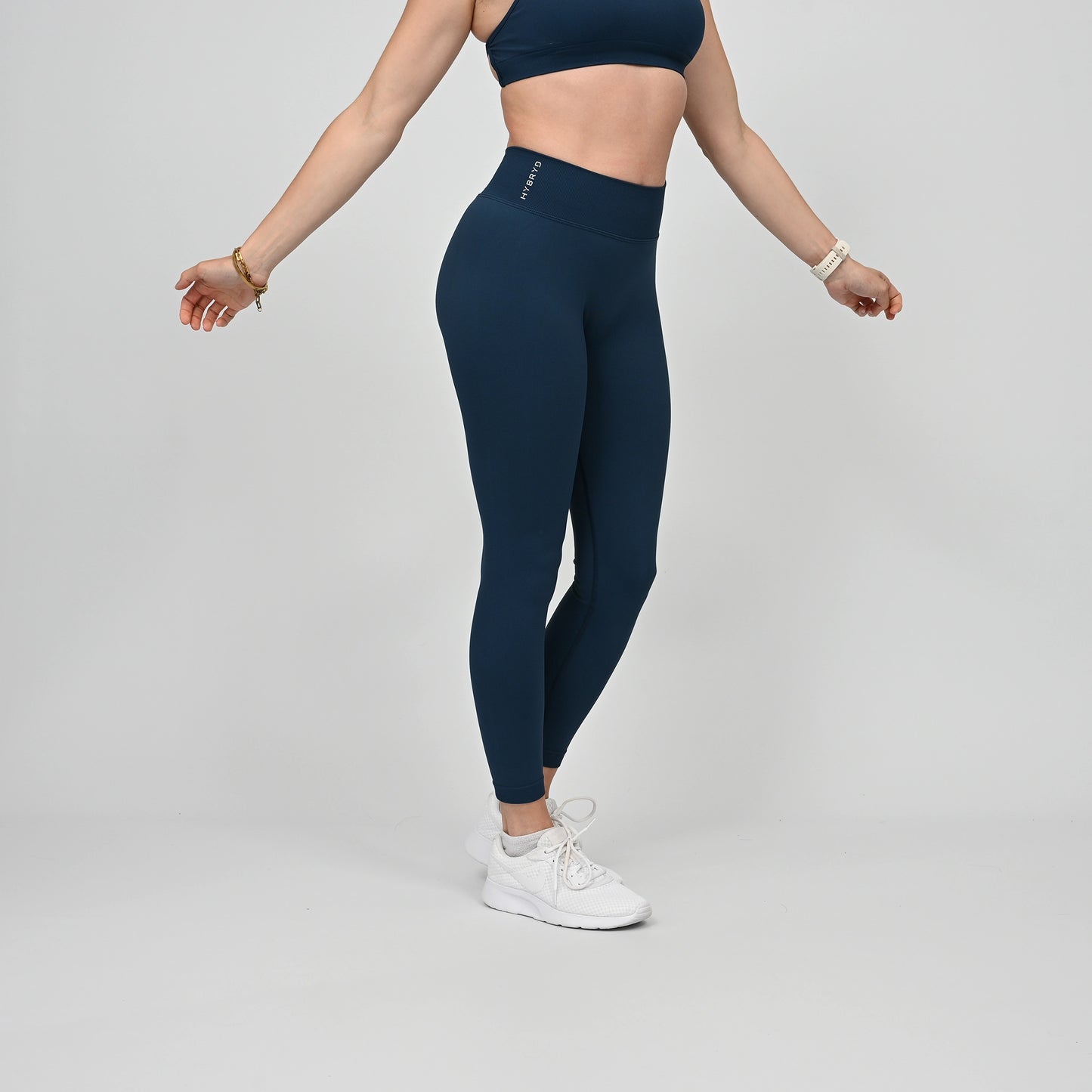 Girl wearing teal Hybryd equinox leggings that have a v-dip rear waist and a scrunch bum. From activewear brand Hybryd