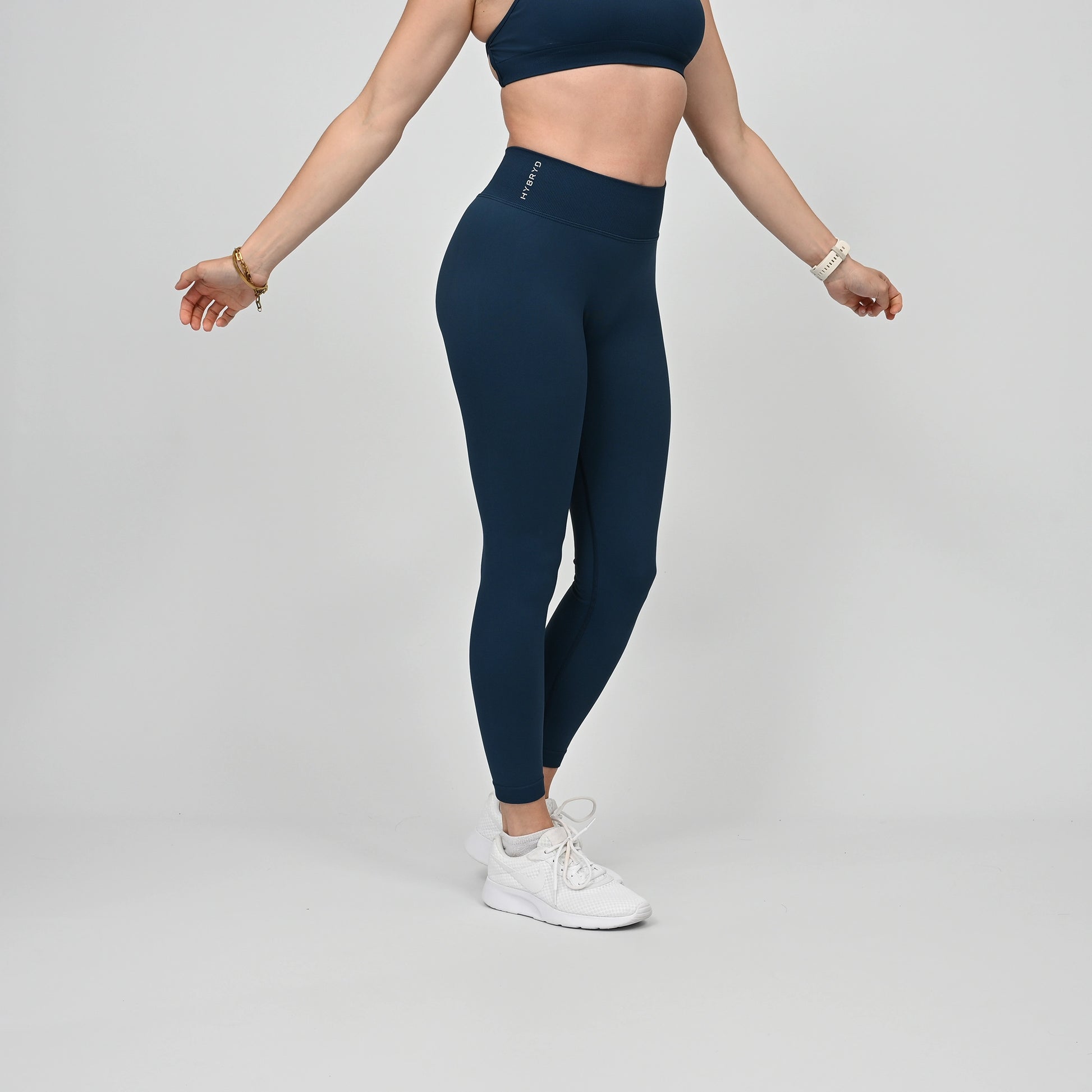 Girl wearing teal Hybryd equinox leggings that have a v-dip rear waist and a scrunch bum. From activewear brand Hybryd