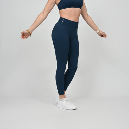 Girl wearing teal Hybryd equinox leggings that have a v-dip rear waist and a scrunch bum. From activewear brand Hybryd