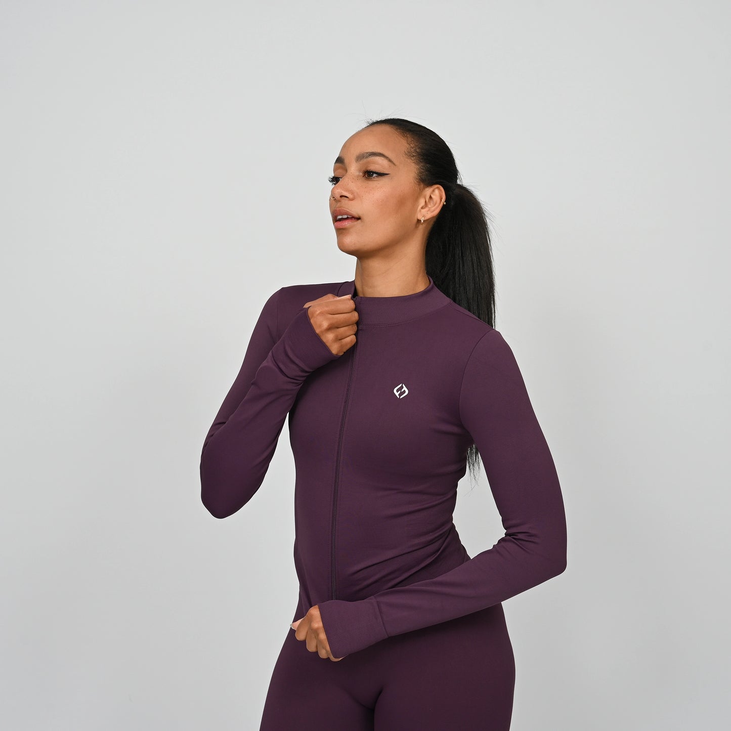 Woman wearing a purple matching gym outfit with a Hybryd logo on a light gray background
