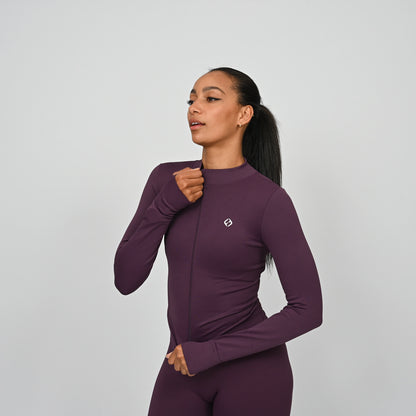 Woman wearing a purple matching gym outfit with a Hybryd logo on a light gray background