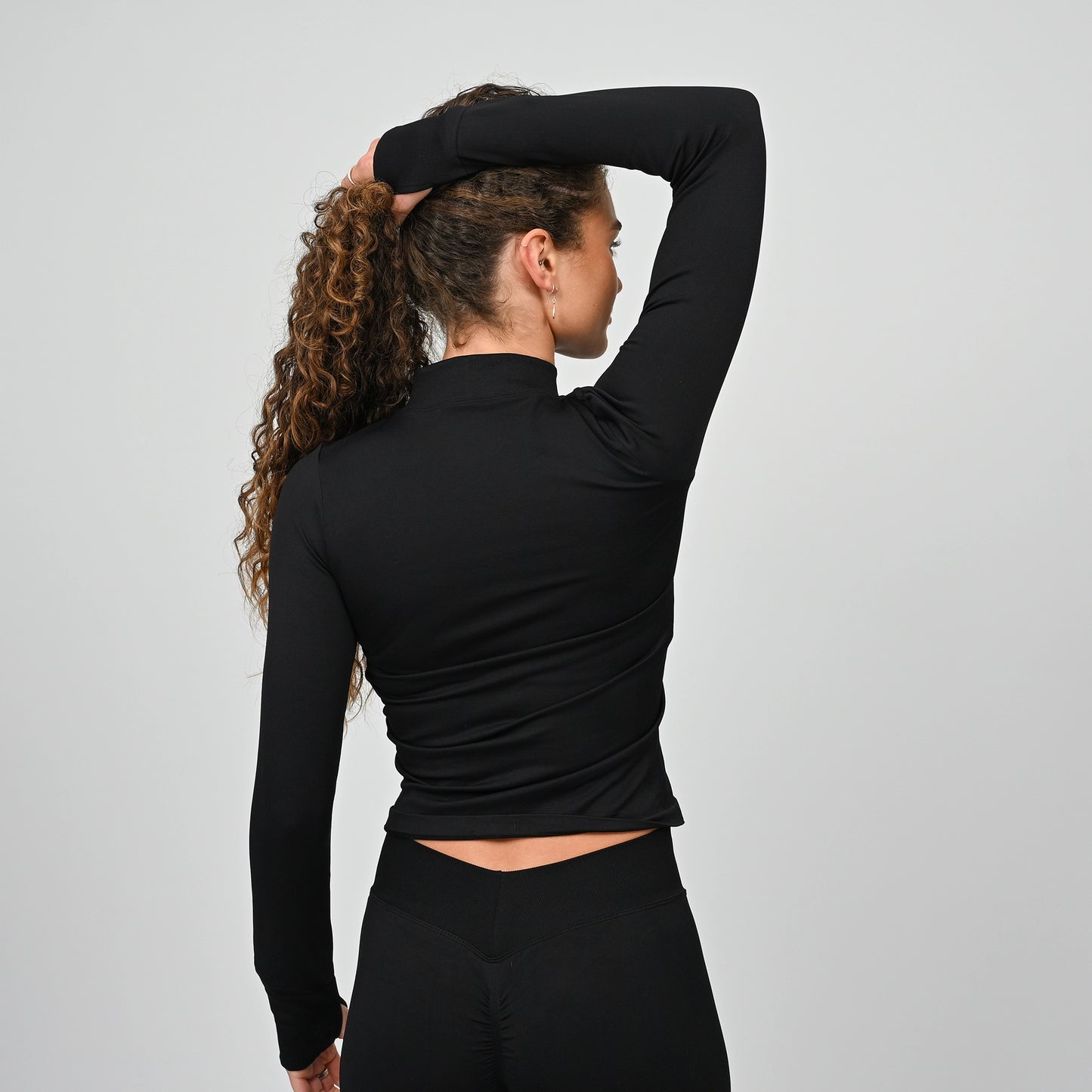 Athlete wearing a black long-sleeve training top with a high neckline on a gray background