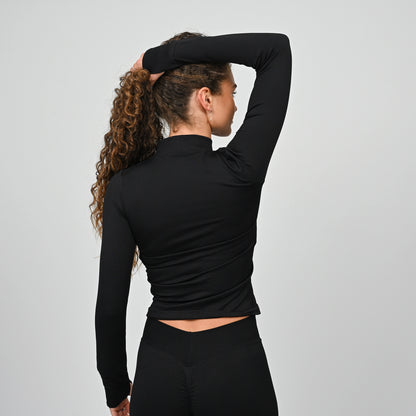 Athlete wearing a black long-sleeve training top with a high neckline on a gray background