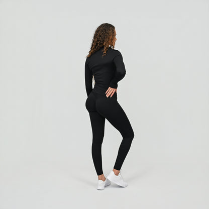 Person wearing a black outfit with scrunch bum leggings and a zip up gym top on a light gray background