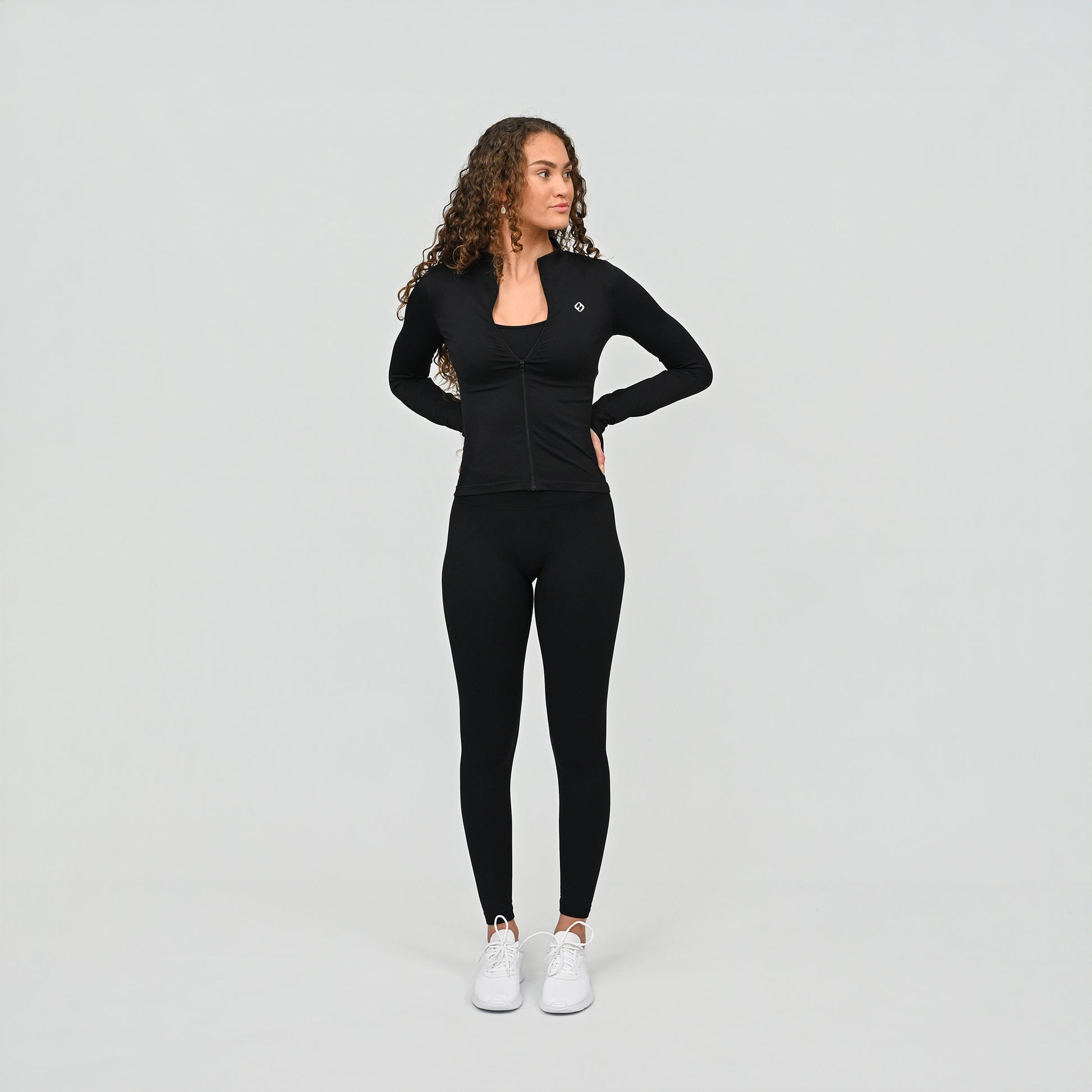 Woman wearing a black athletic matching crossfit gym outfit on a light gray background
