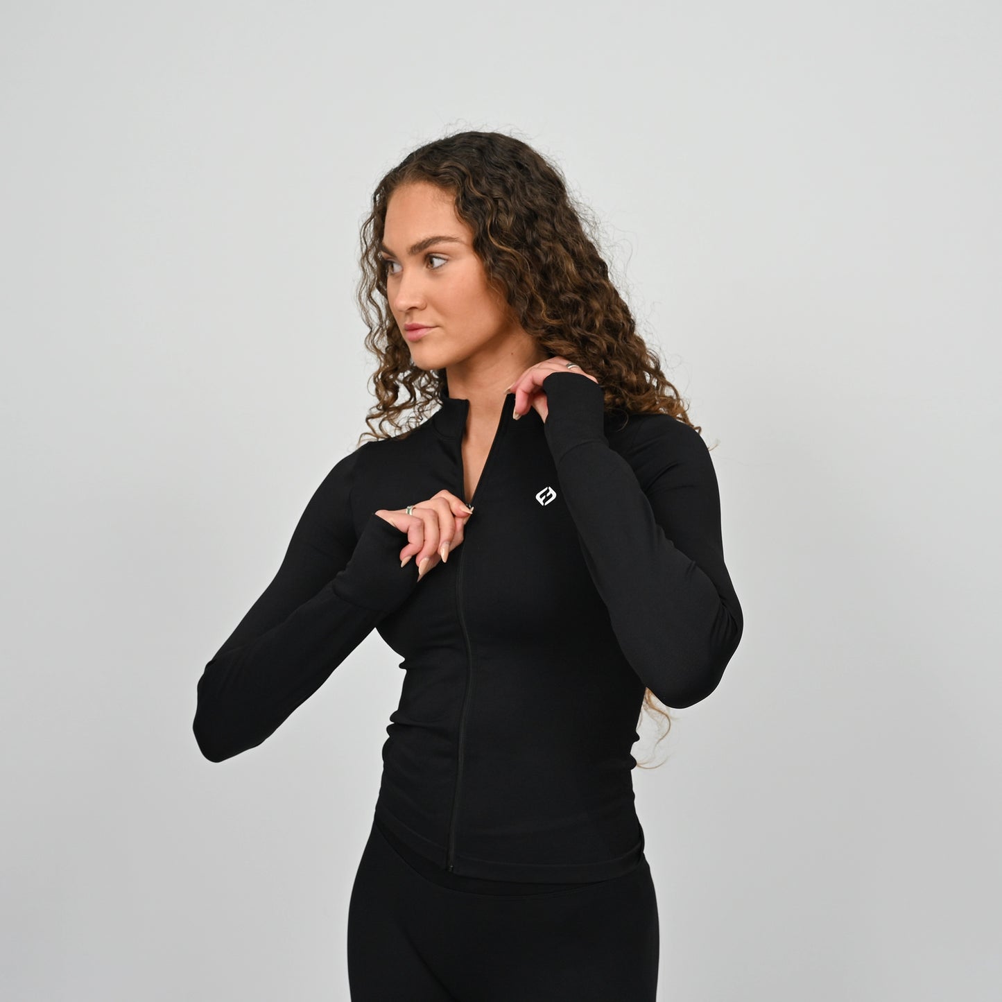 Woman wearing a black matching set training outfit with a Hybryd logo on a light gray background