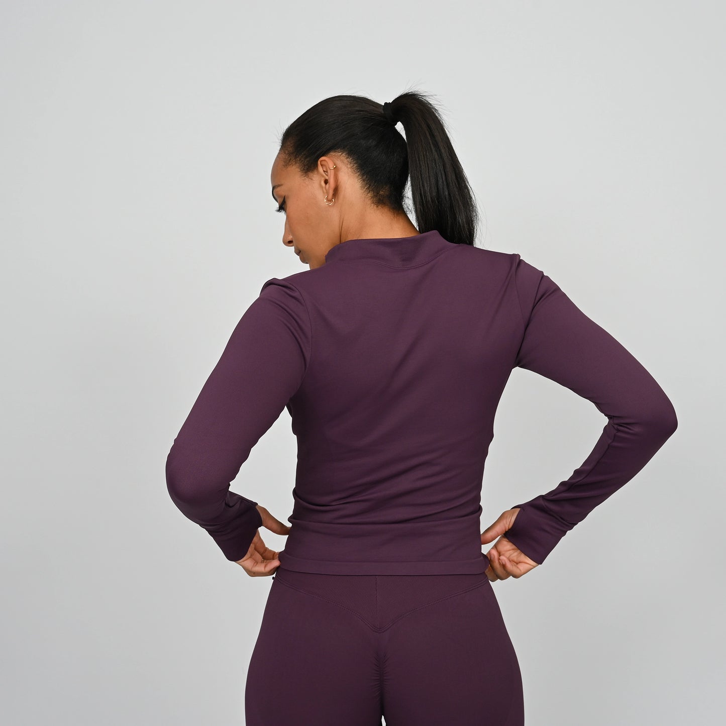 Person wearing a purple long sleeved athletic outfit on a gray background