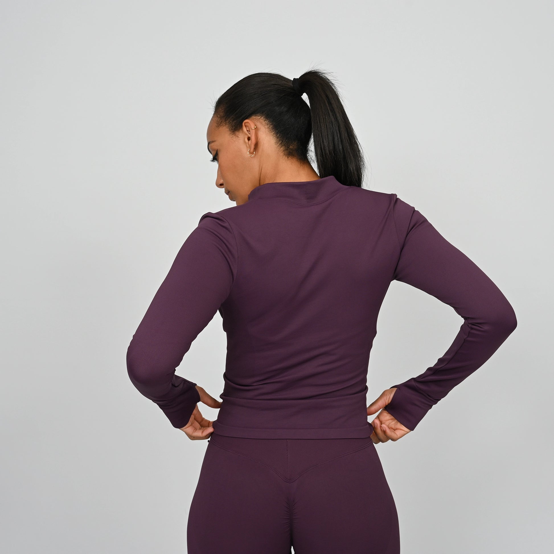 Person wearing a purple long sleeved athletic outfit on a gray background