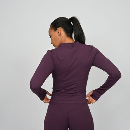 Person wearing a purple long sleeved athletic outfit on a gray background