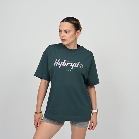 Woman wearing a green unisex t-shirt with 'Hybryd' logo on a gray background