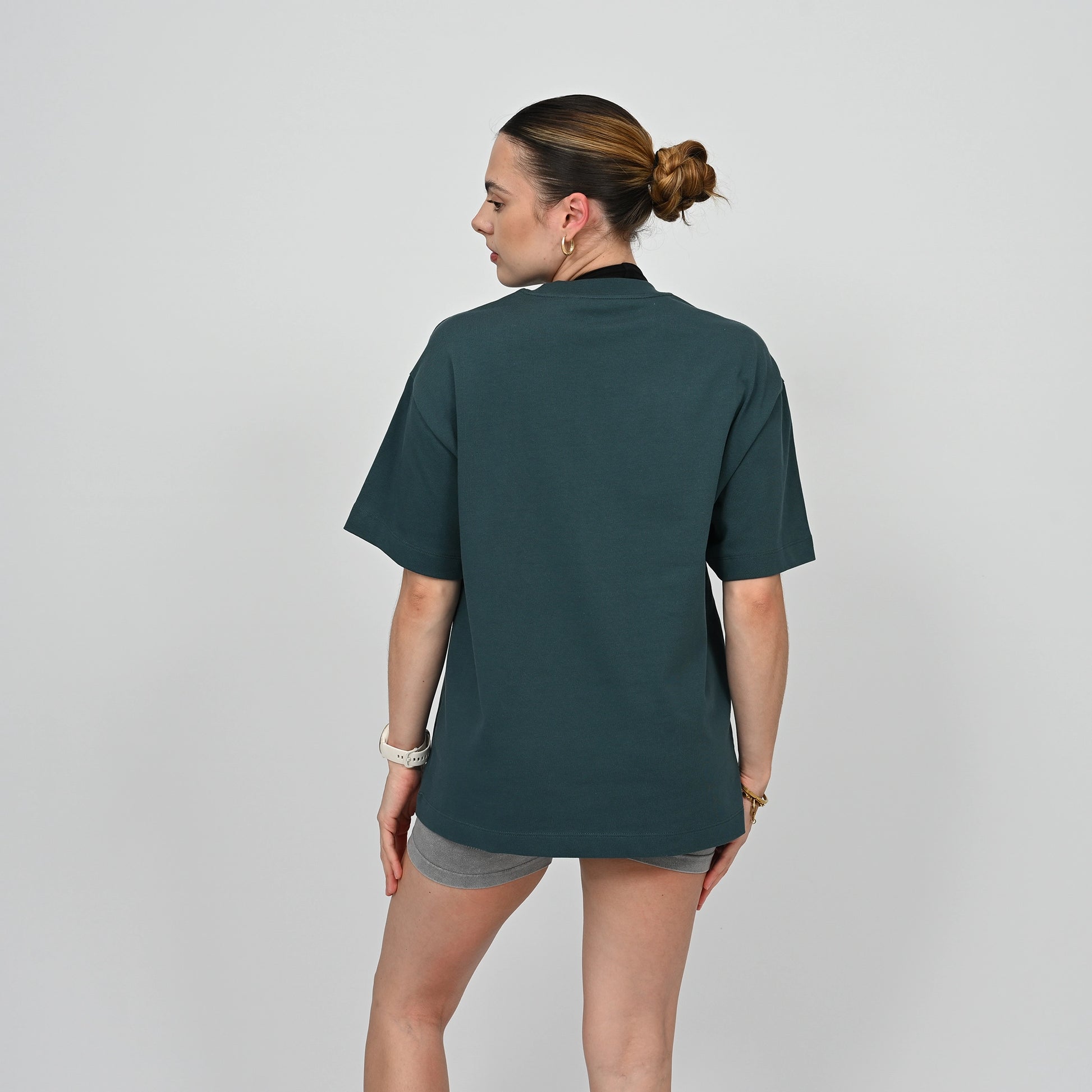 Person wearing a dark green unisex t-shirt on a plain background