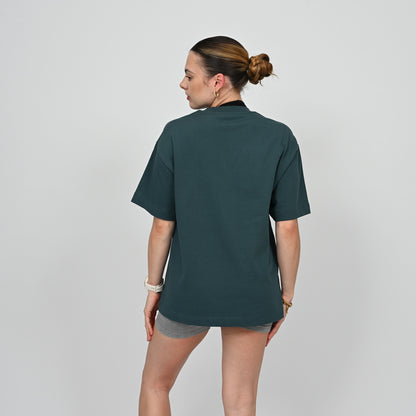 Person wearing a dark green unisex t-shirt on a plain background