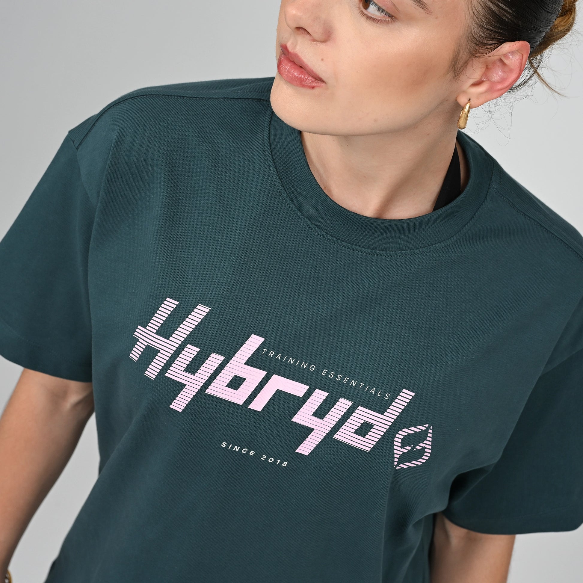 Person wearing an oversize green t-shirt with 'Hybryd' logo and text on a plain background