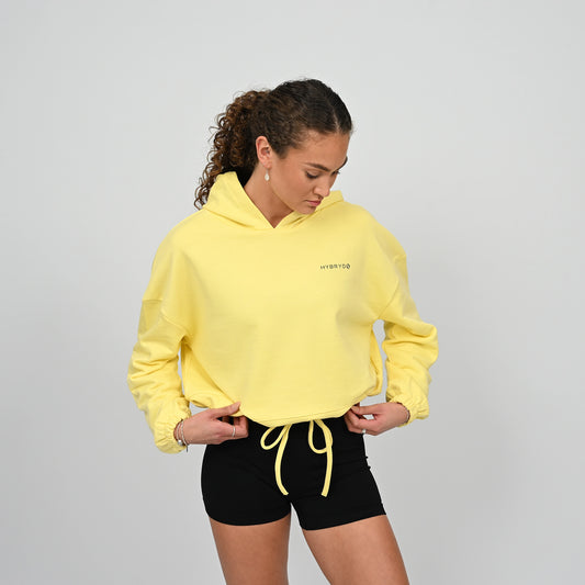 Woman wearing a yellow hoodie. Cropped oversized hoodie. Dropped shoulders, oversized relaxed fit with a drawstring fastening