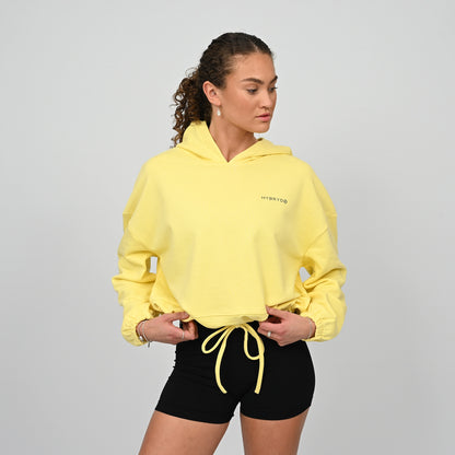 Woman wearing a cropped oversized hoodie. Dropped shoulders, oversized relaxed fit with a drawstring fastening from the gymwear brand hybryd.