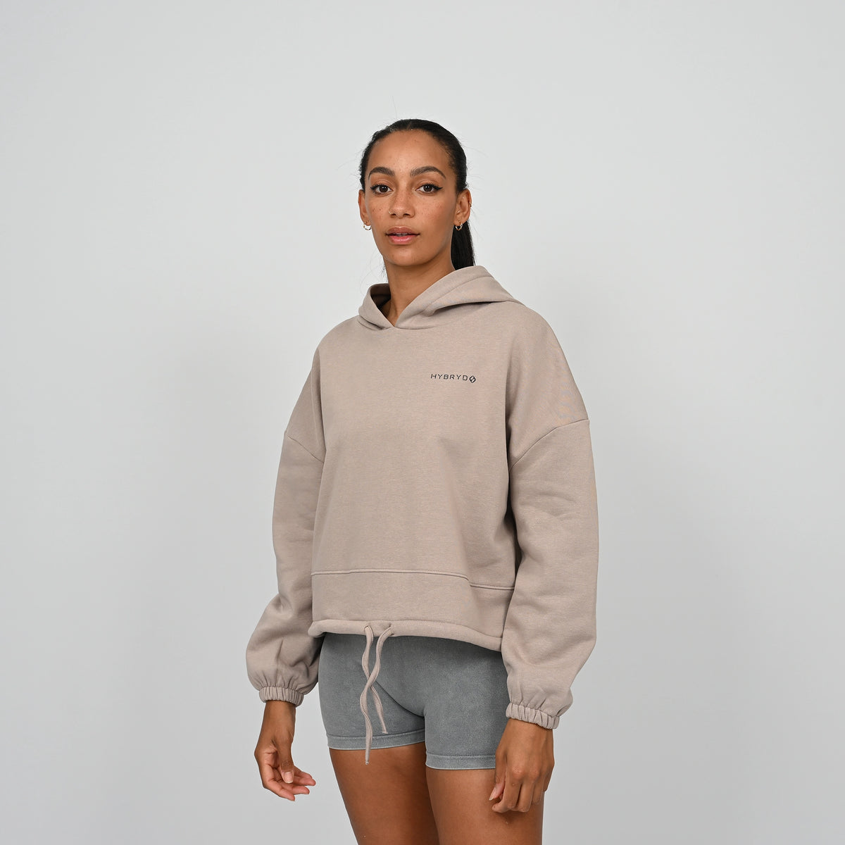 Person wearing a beige oversized hoodie with a Hybryd logo on a plain background