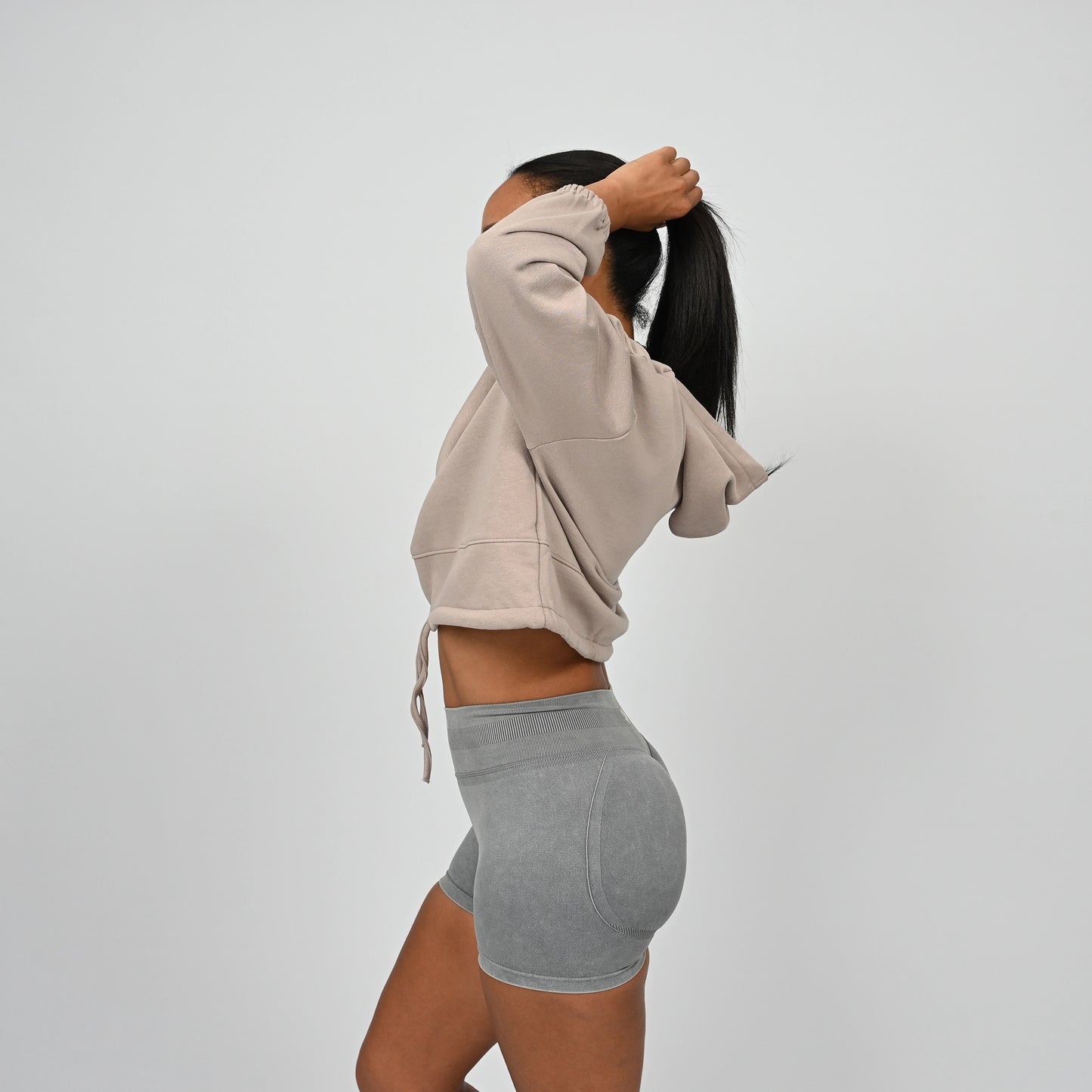 Person wearing a cropped post training hoodie with drawstring and grey scrunch bum shorts