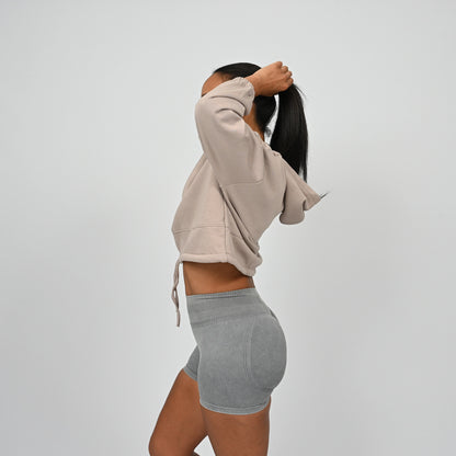 Person wearing a cropped post training hoodie with drawstring and grey scrunch bum shorts