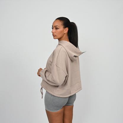 Woman wearing a beige hoodie from gymwear brand Hybryd