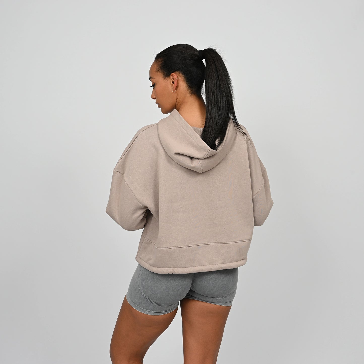 Person wearing a beige Hybryd hoodie and grey bootie shorts on a plain background
