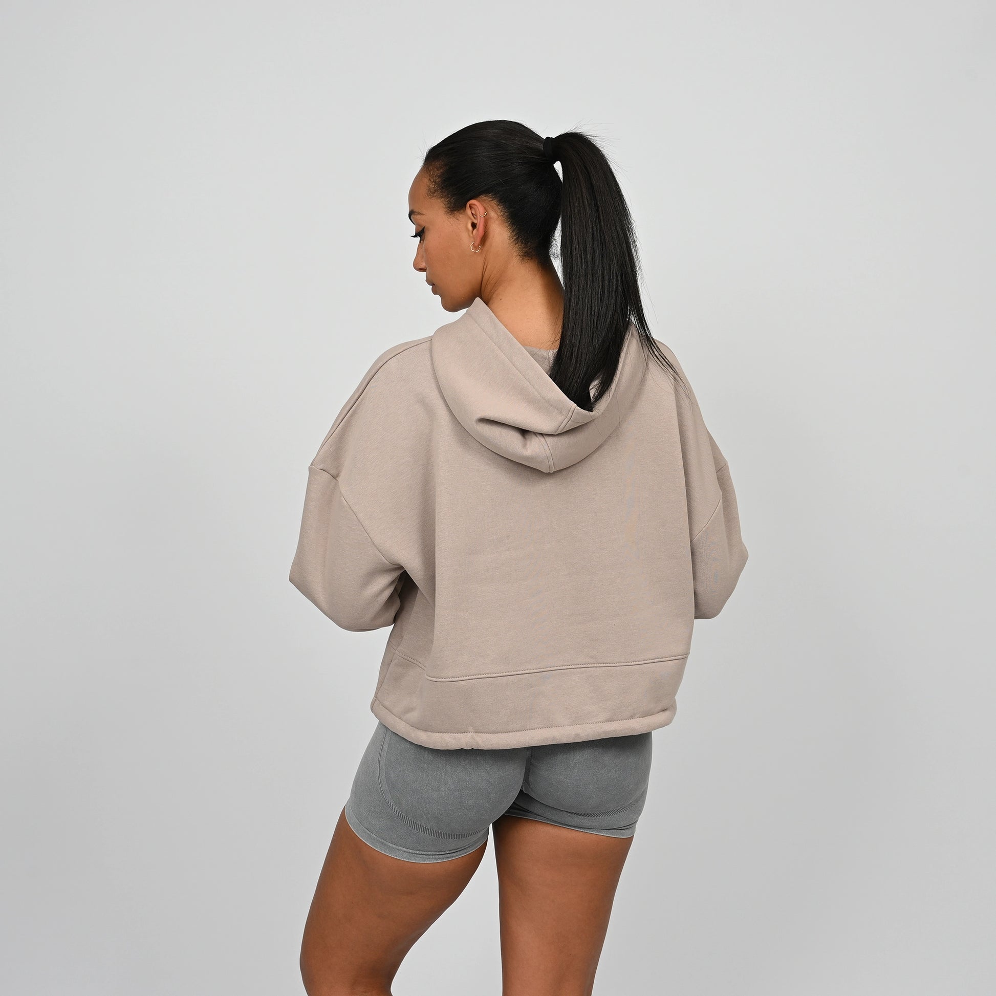 Person wearing a beige Hybryd hoodie and grey bootie shorts on a plain background