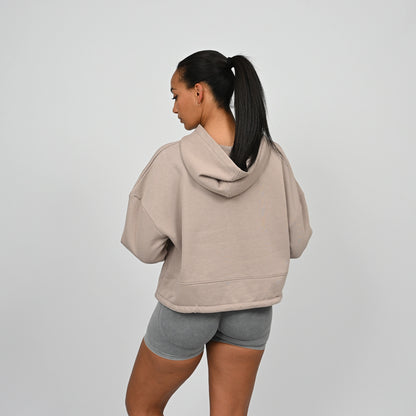Person wearing a beige Hybryd hoodie and grey bootie shorts on a plain background