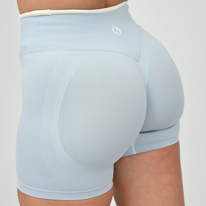 Hyrox athlete wearinga pair of powder blue booty shorts with white piping. High waisted with a cinch bum and contouring.  From the brand Hybryd.