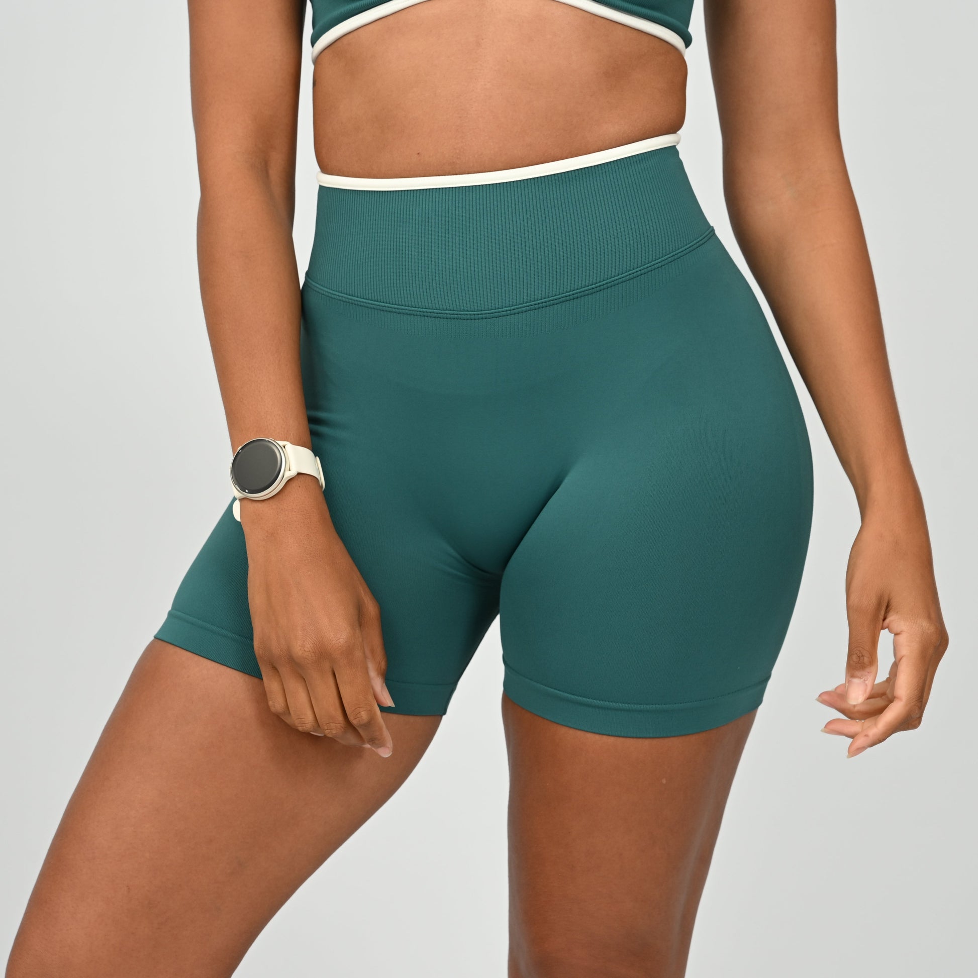Hyrox athlete wearinga pair of Jade green booty shorts with white piping. High waisted with a cinch bum and contouring. From the brand Hybryd.