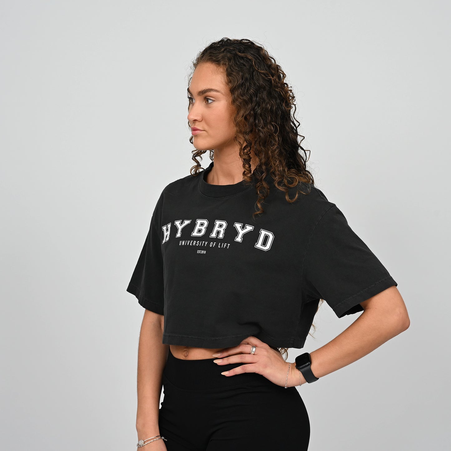 Person wearing a black cropped 'HYBRYD' t-shirt on a grey background