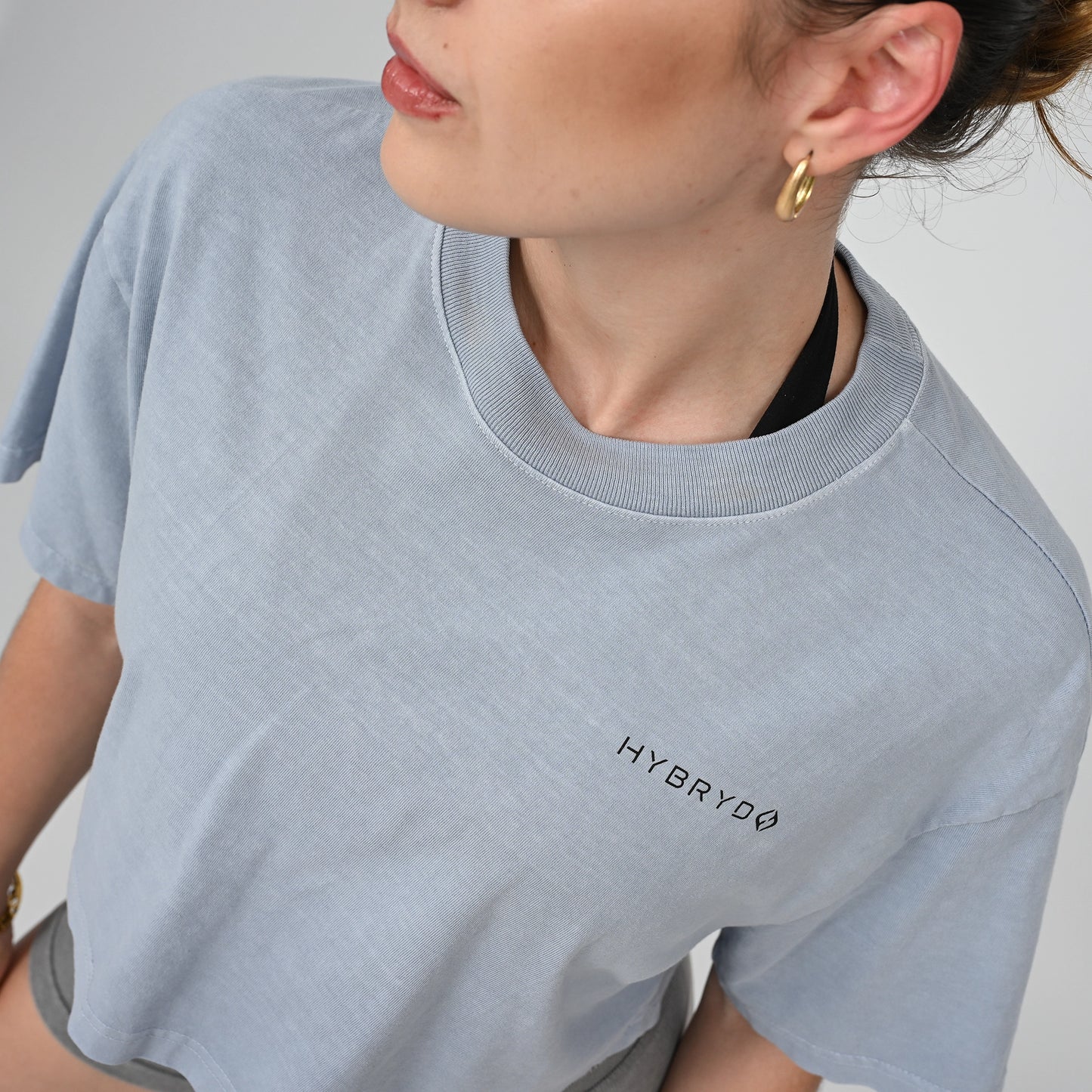 Person wearing a light blue t-shirt with 'HYBRYD' logo on a plain background