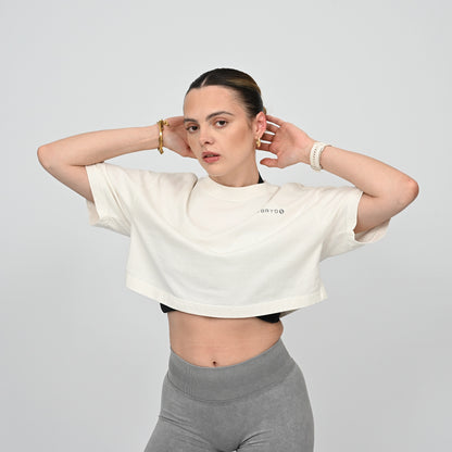 Woman wearing a white crop top and grey leggings from Hybryd, against a plain background