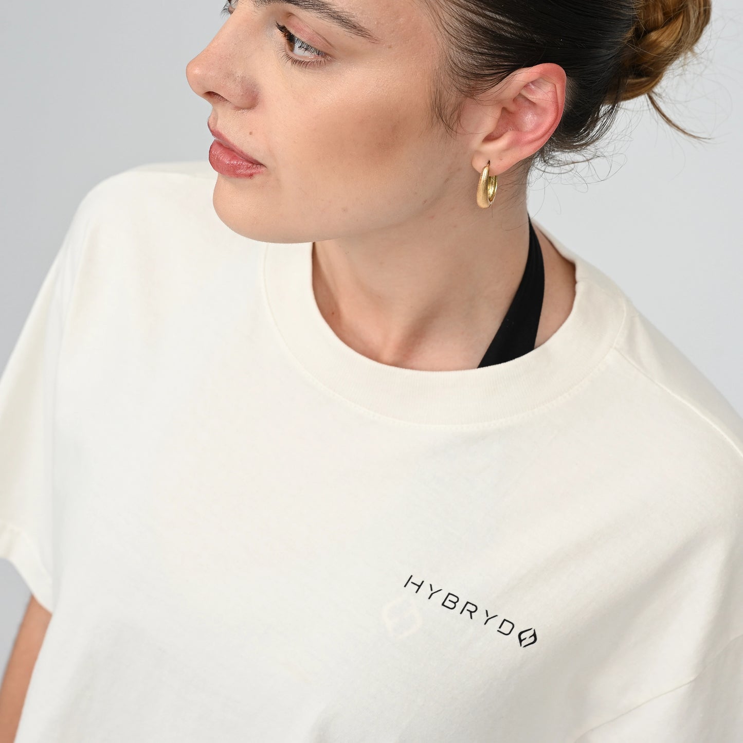 Person wearing a white t-shirt with 'HYBRYD' logo on a plain background