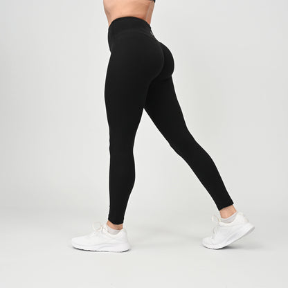 Person wearing black gym leggings with scrunch bum and white sneakers on a light gray background