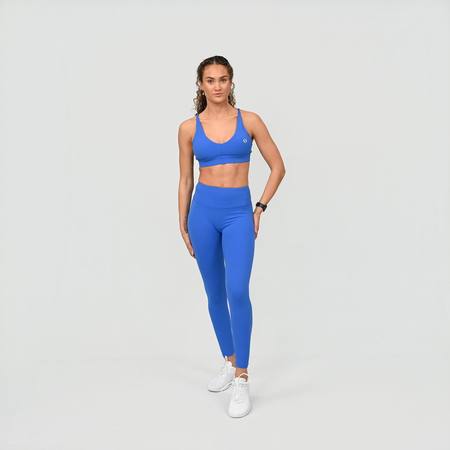 Woman wearing a blue athletic gym work out matching set outfit on a light gray background