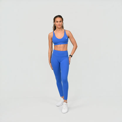 Woman wearing a blue athletic gym work out matching set outfit on a light gray background
