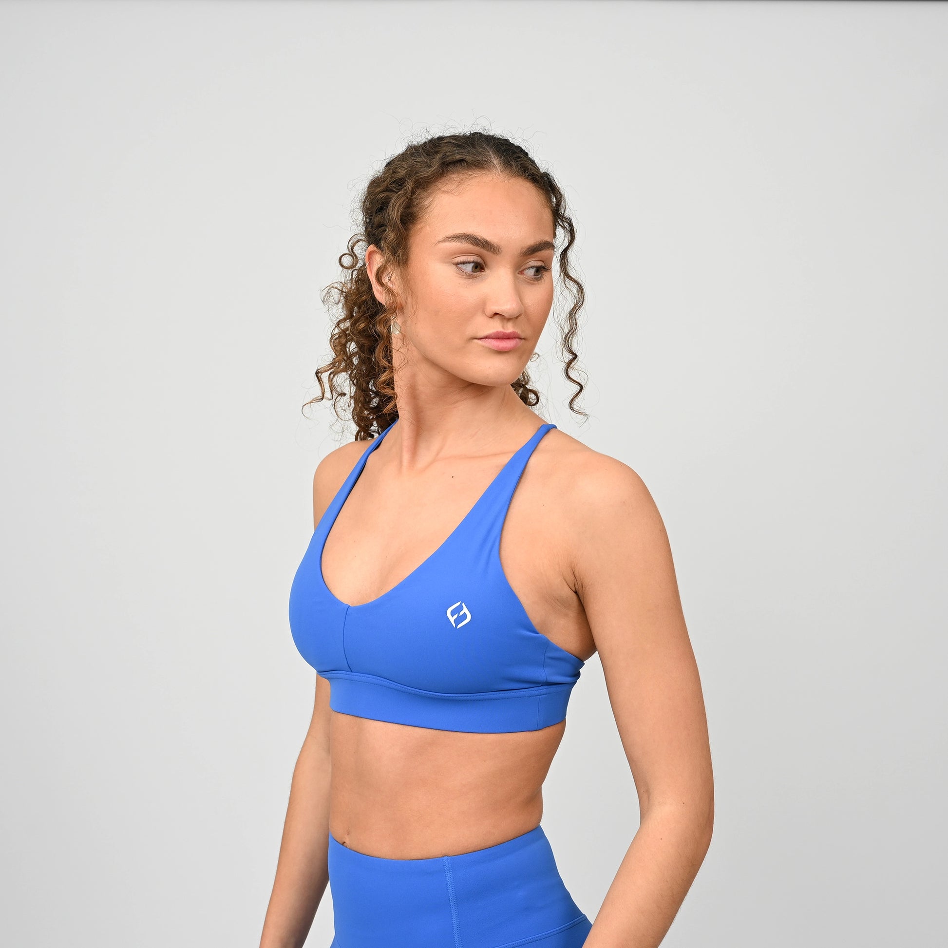 Woman wearing a royal blue sports bra and leggings on a light gray background