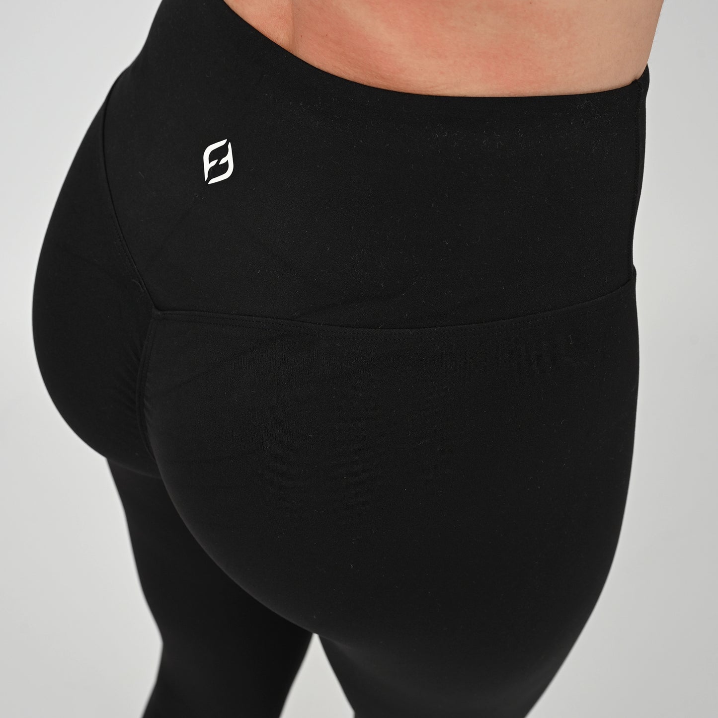 Black contouring gym leggings with a bum scrunch and logo on a gray background
