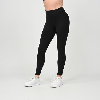 Person wearing black crossfit workout gym leggings with high waist and white sneakers on a gray background