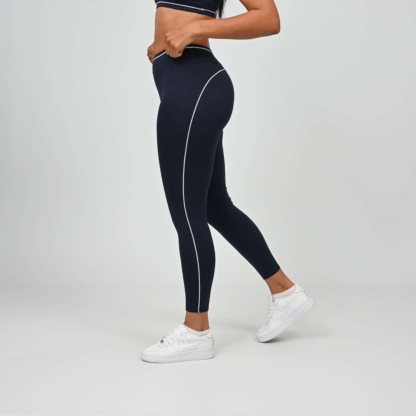 Hybrid yoga athlete wearing a navy crossfit gym outfit with white stripes on a gray background from Hybryd